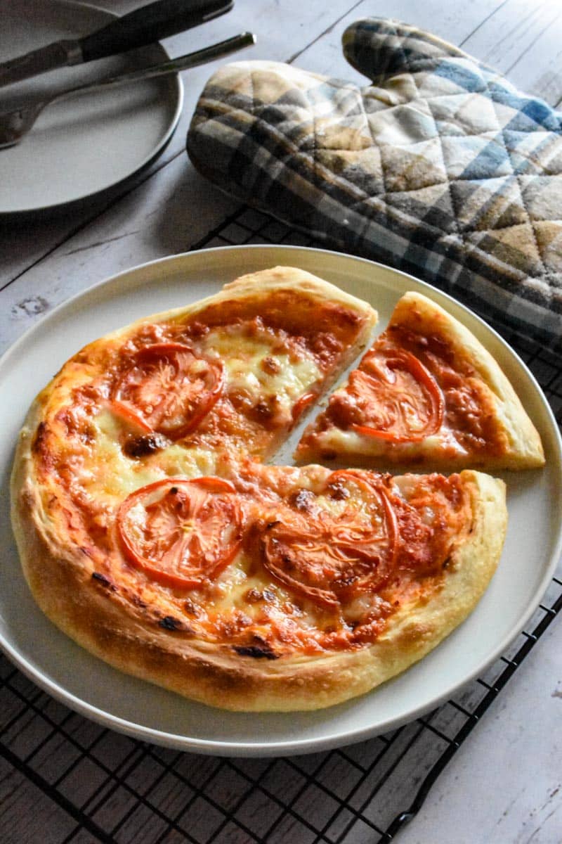 sourdough pizza with cheese and sliced tomatoes on a white plate