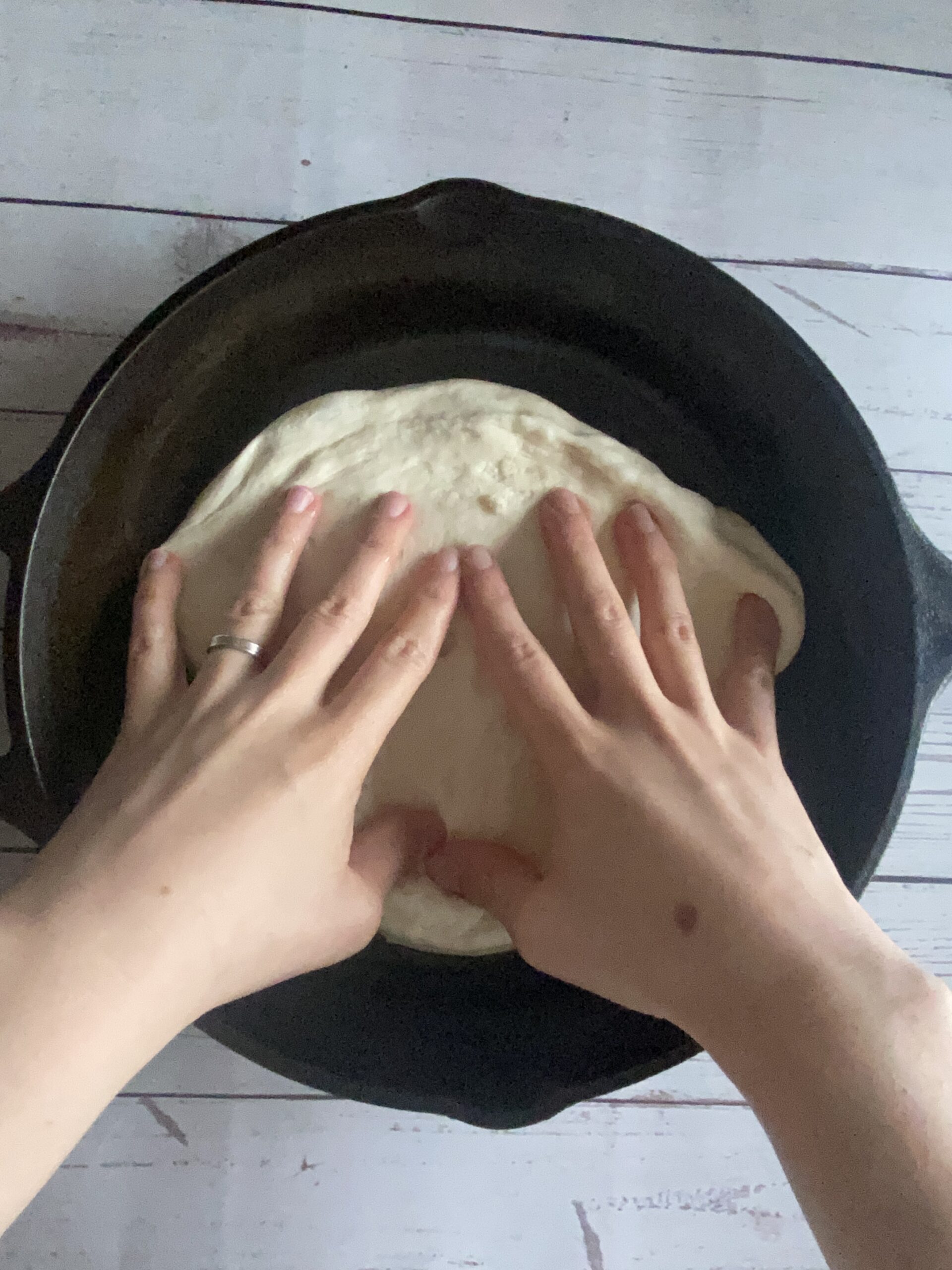 stretch the sourdough pizza dough into the cast iron skillet
