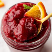 the best ever homemade orange cranberry sauce in a small mason jar with a spoon