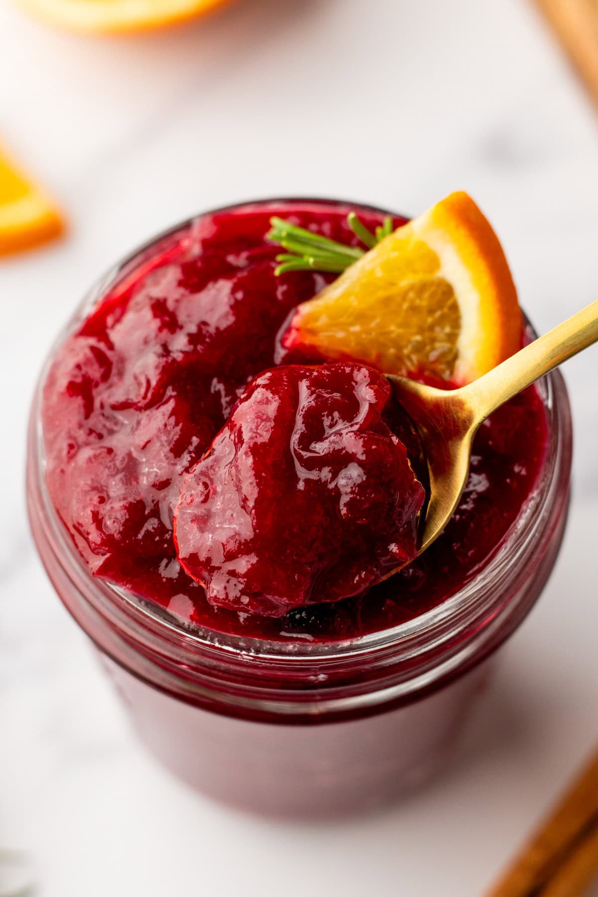 a spoonful of homemade cranberry sauce made with orange juice over a mason jar of cranberry sauce
