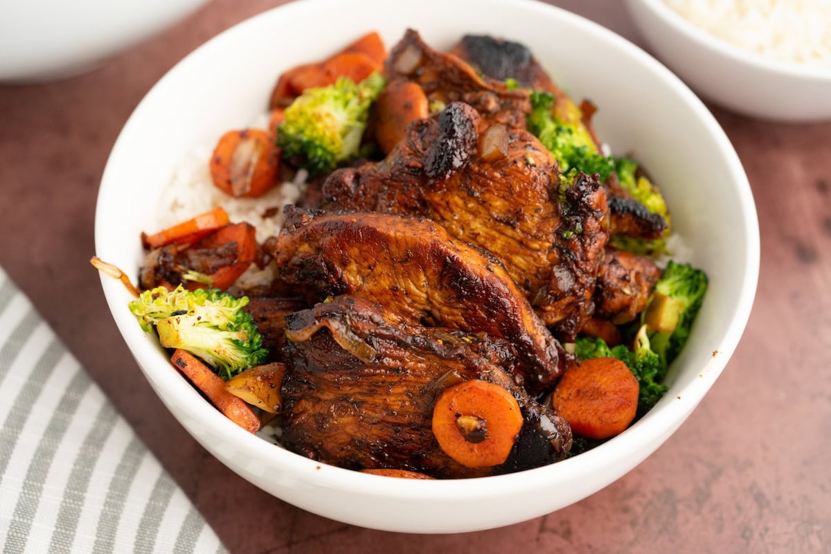a close up of Balsamic Chicken and Veggies over rice in a white bowl