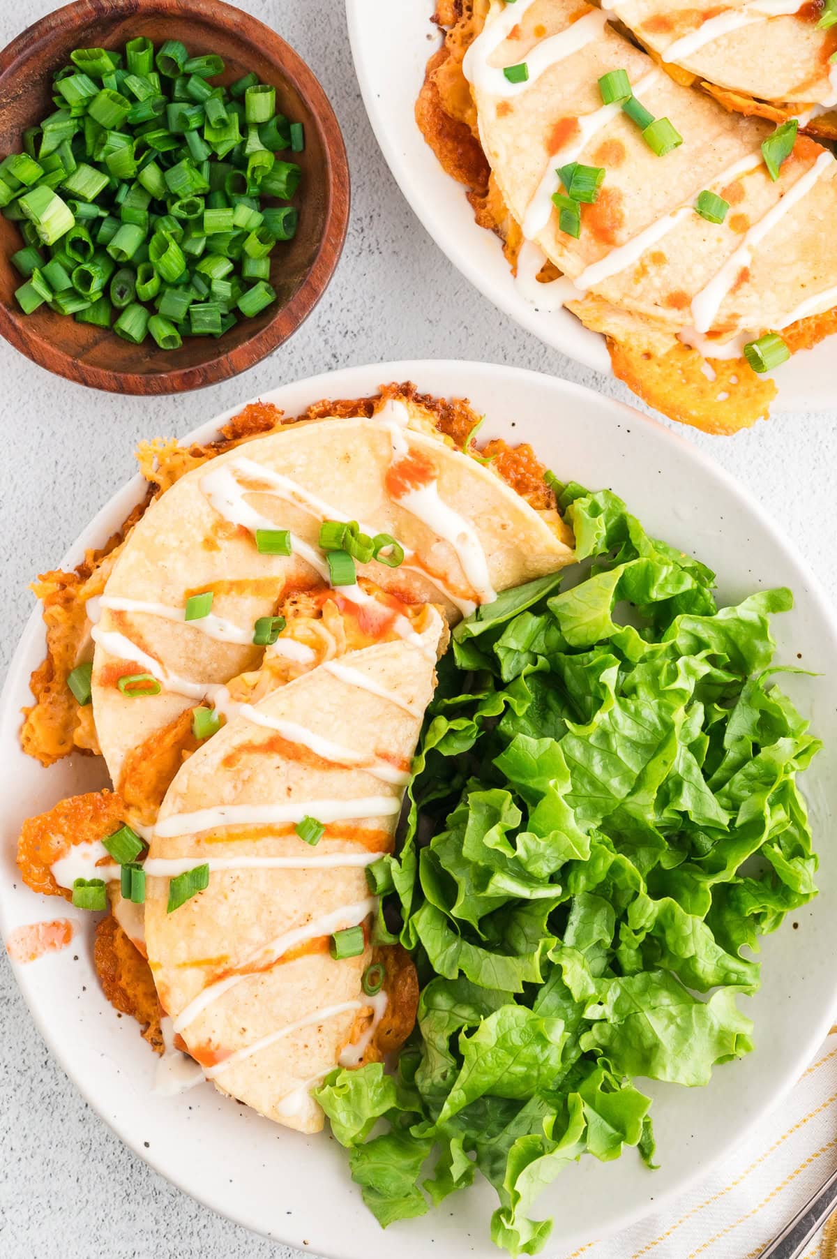 two oven baked Buffalo chicken tacos on a plate with fresh greens and green onions