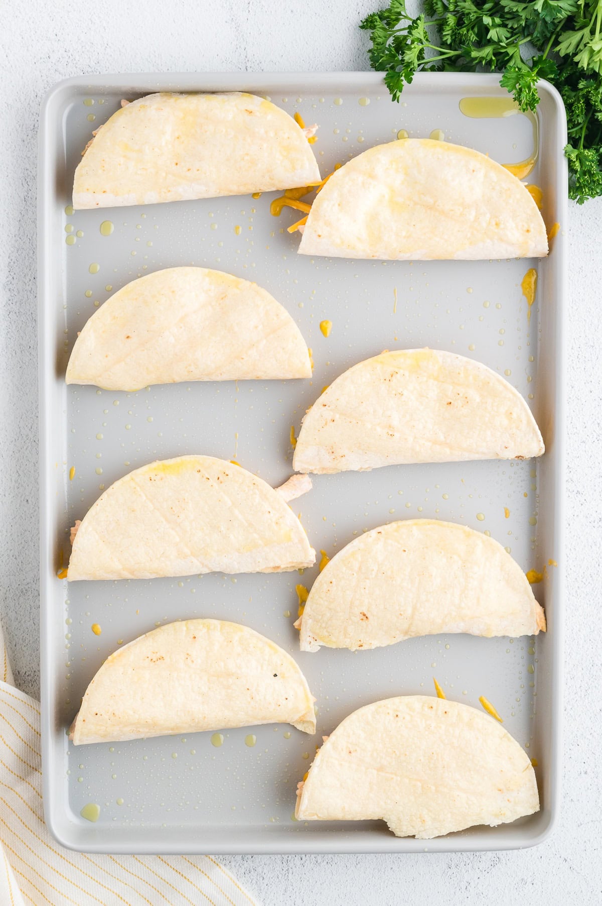 eight Buffalo chicken tacos on a baking sheet