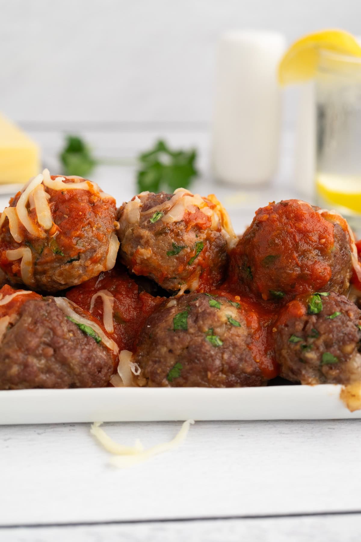 oven baked meatballs smothered in spaghetti sauce and melted cheese on a white platter