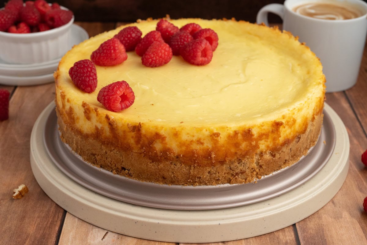gluten free cheesecake with a pecan crust topped with fresh red raspberries