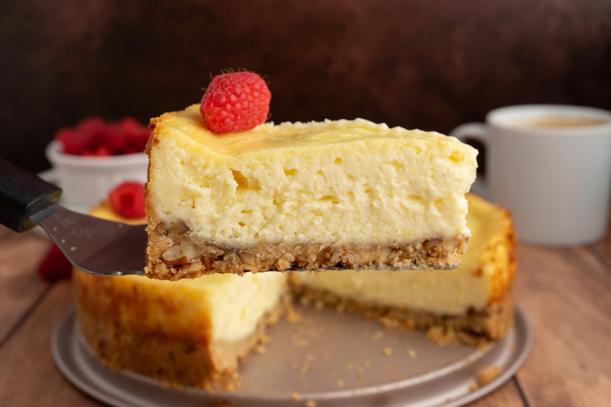one slice of Gluten-Free Pecan Crust Cheesecake topped with a red raspberry