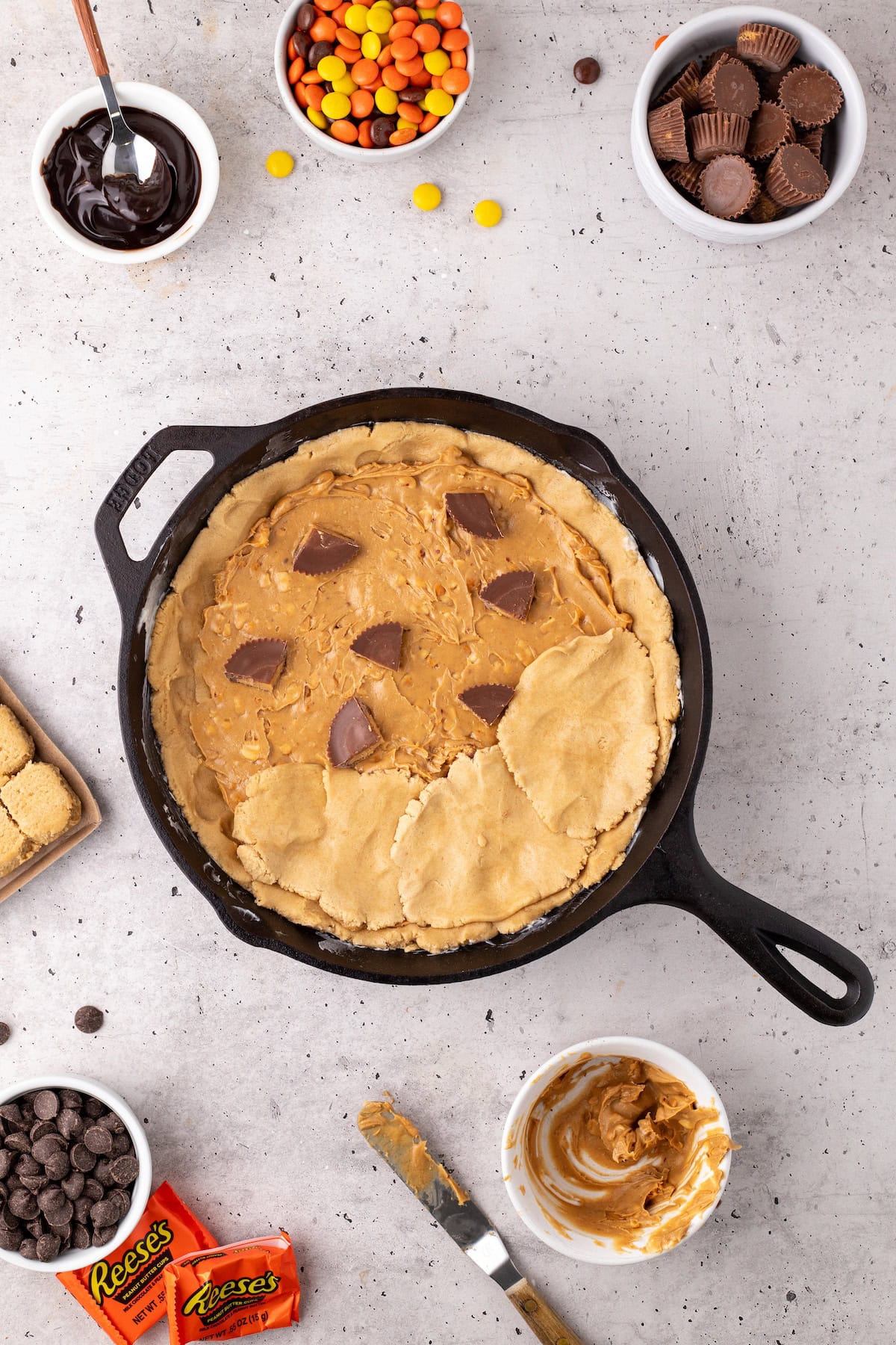 cover the layers with more peanut butter cookie dough and spread it out to cover the whole skillet