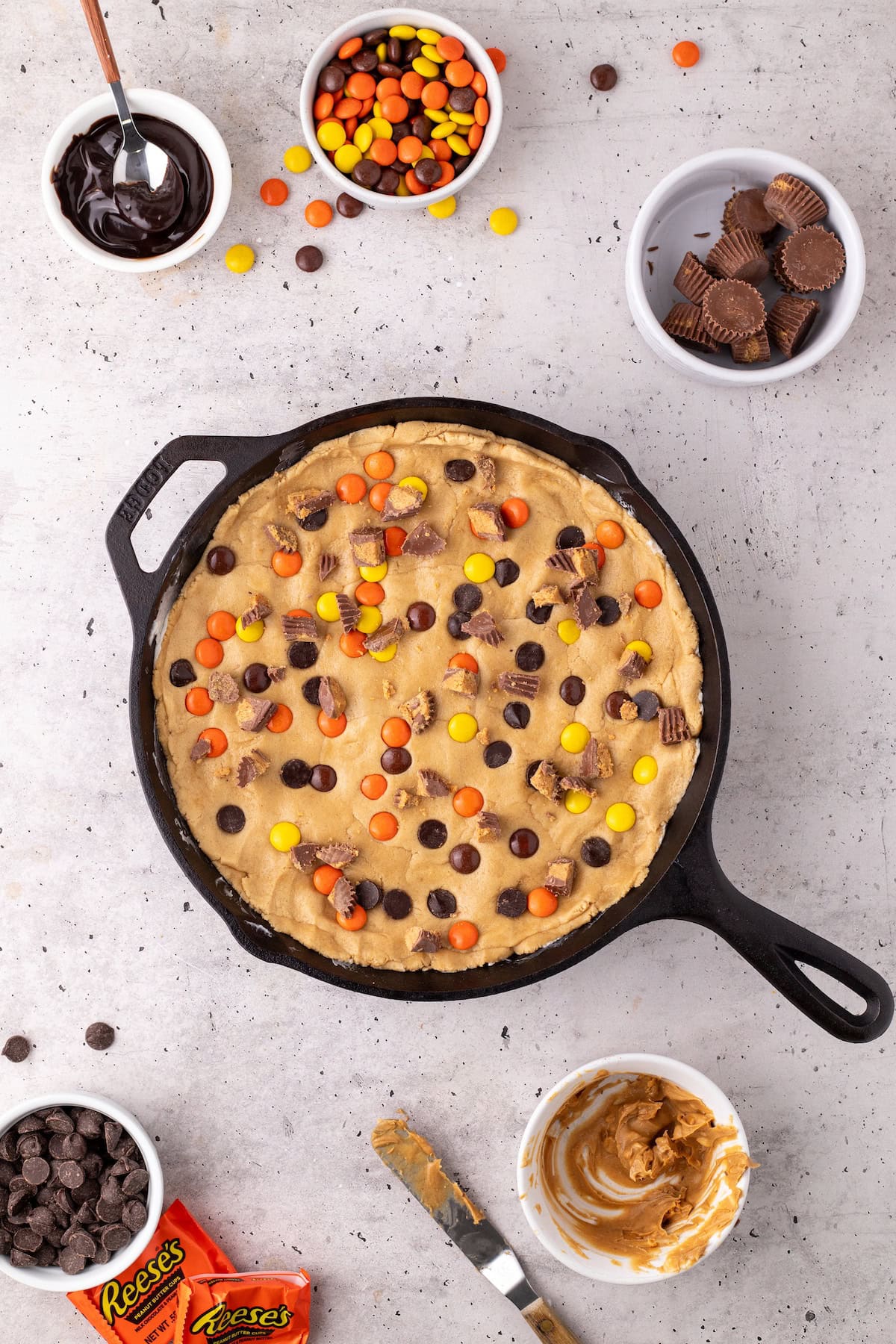 top the cookie cake with more PB cups, Reese's Pieces, and chocolate chips