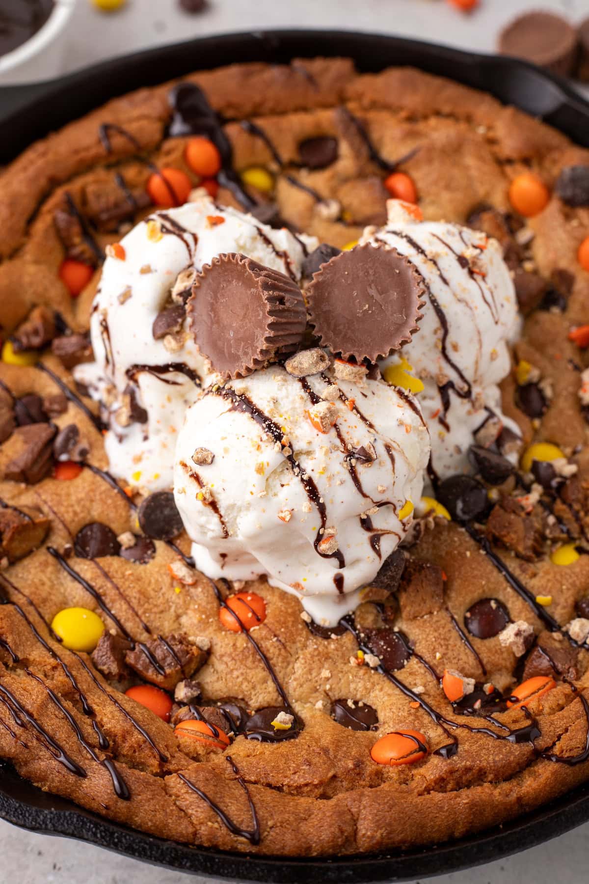 peanut butter skillet cookie topped with hot fudge, vanilla ice cream, and mini Reese's Peanut Butter Cups