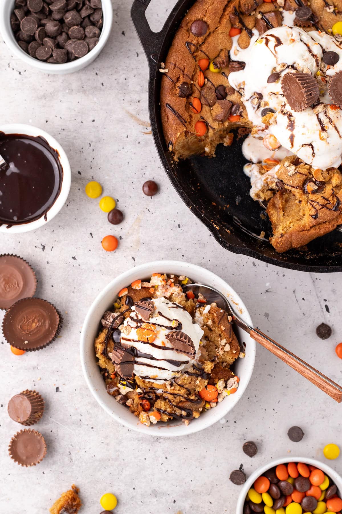 one serving of peanut butter skillet cookie in a white bowl topped with ice cream and hot fudge