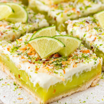 a tray of easy key lime pie bars topped with key lime slices, toasted coconut, and lime zest