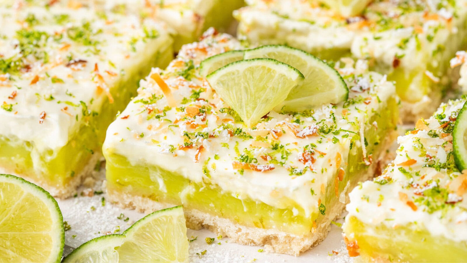 easy key lime pie bars topped with key lime slices, toasted coconut, and lime zest