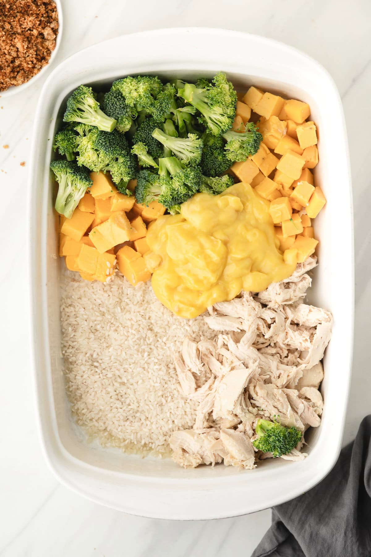 all the ingredients in the baking dish, including velveeta, cream of chicken soup, broccoli, rice, and chicken