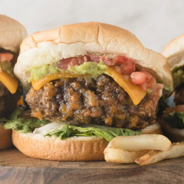 air fryer taco burger topped with guacamole, salsa, and cheddar cheese