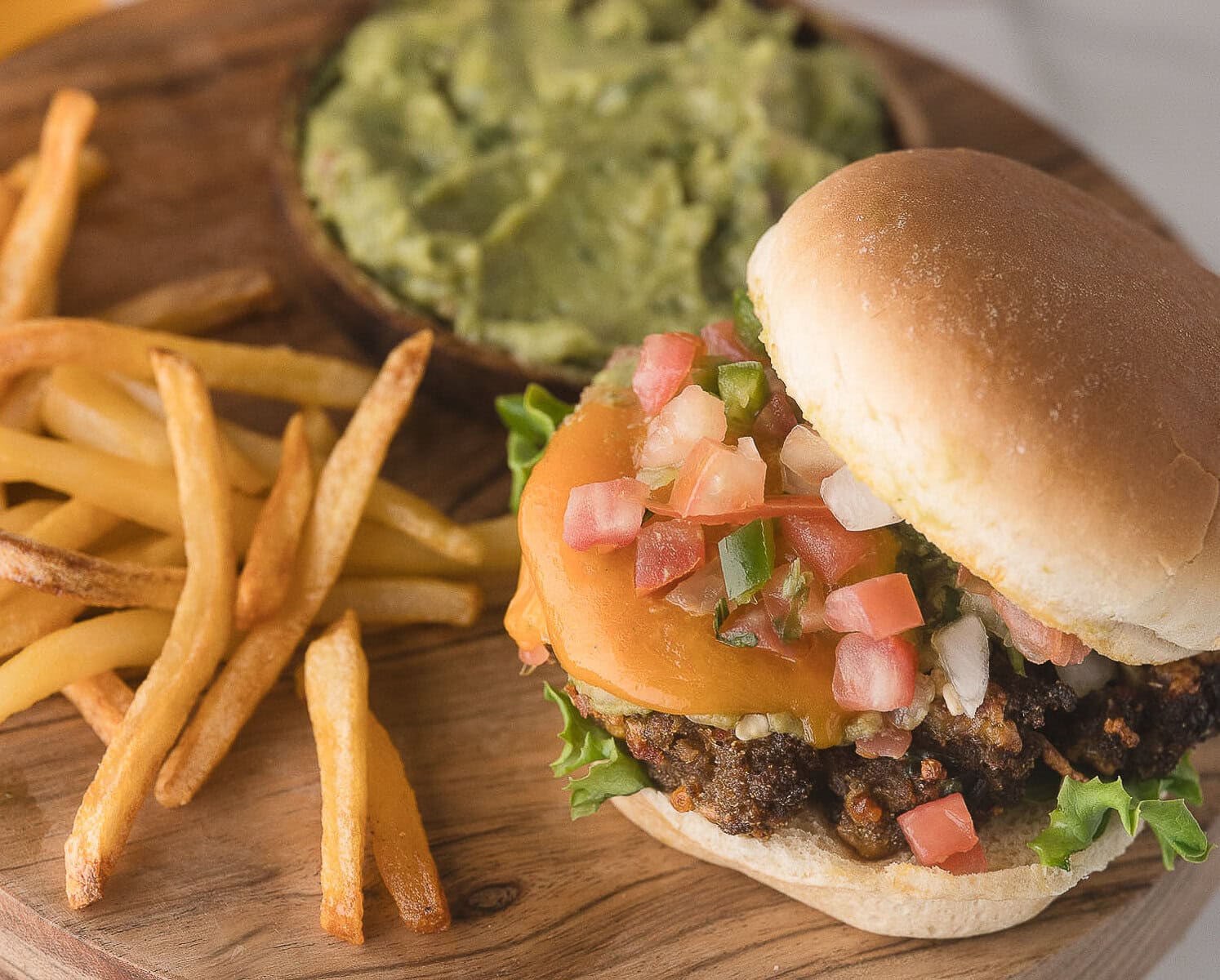 a taco burger with salsa and cheddar cheese and a pile of French fries