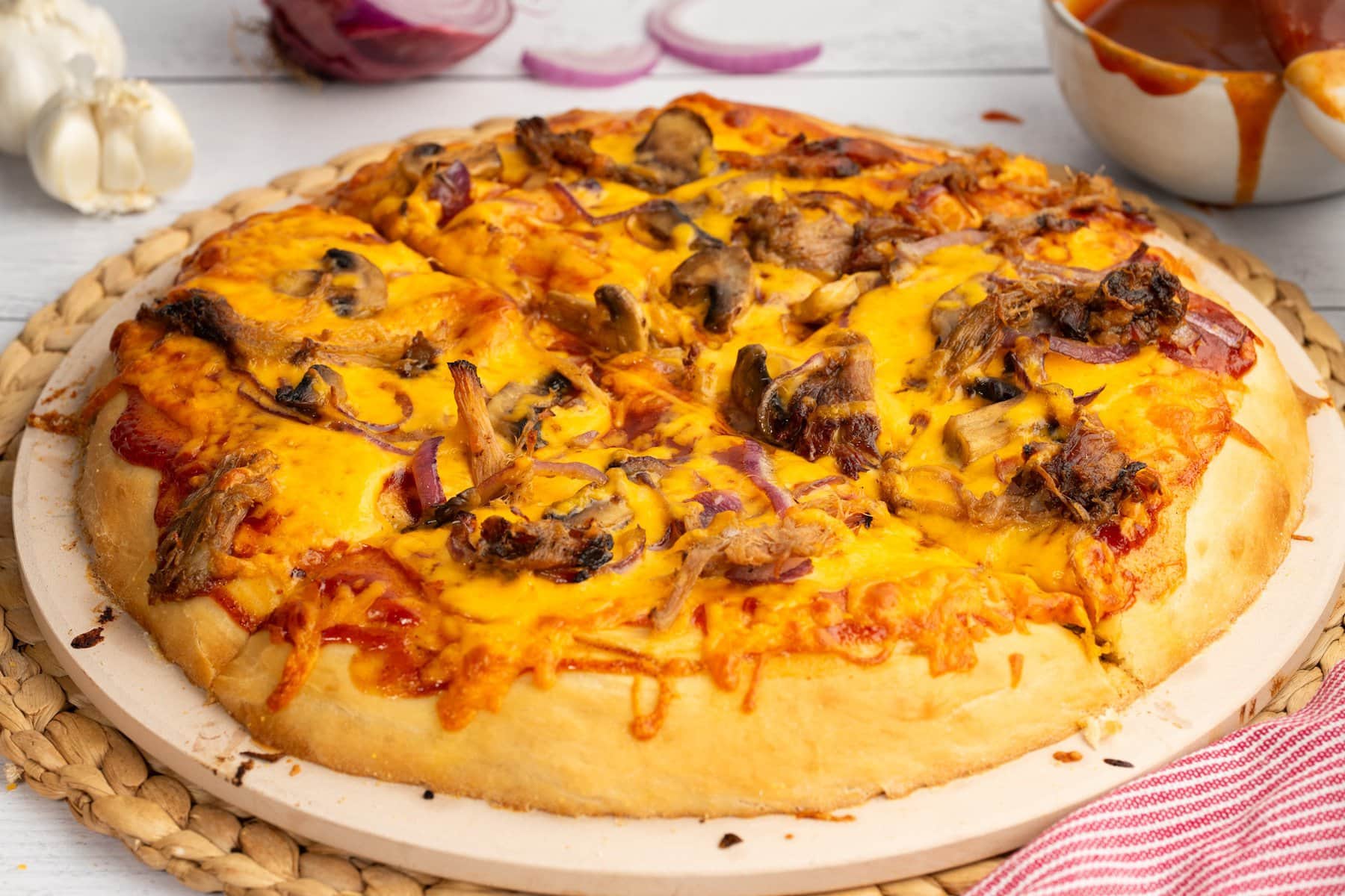 a leftover pulled pork BBQ pizza on a pizza stone