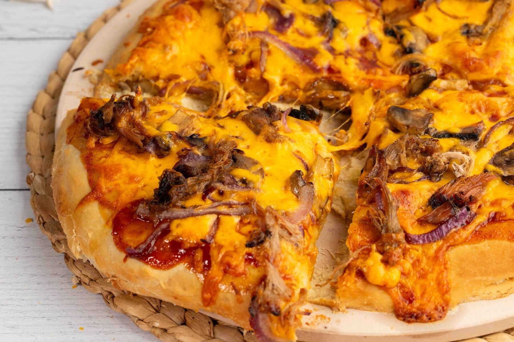 a slice of BBQ pork pizza pulled apart from the rest of the pulled pork pizza