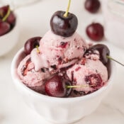 a small dish of no churn homemade cherry ice cream topped with fresh black cherries