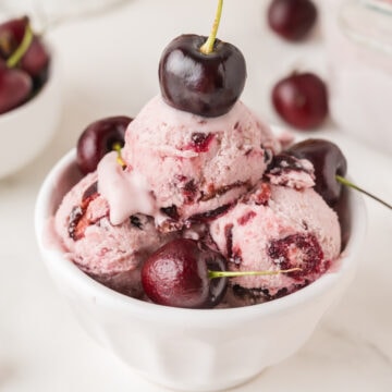 a small dish of no churn homemade cherry ice cream topped with fresh black cherries