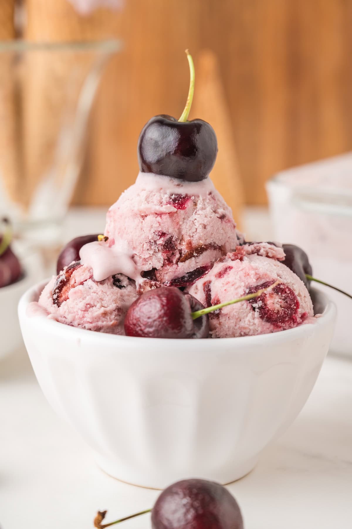 a bowl of homemade black cherry ice cream topped with fresh sweet cherries