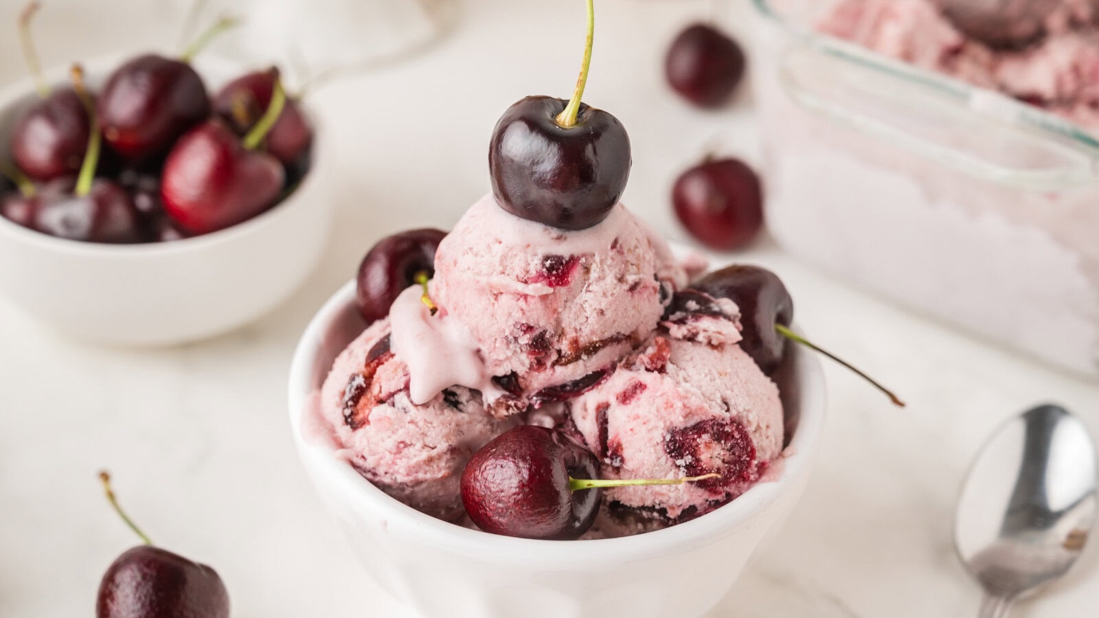 a small dish of no churn black cherry ice cream topped with fresh sweet cherries