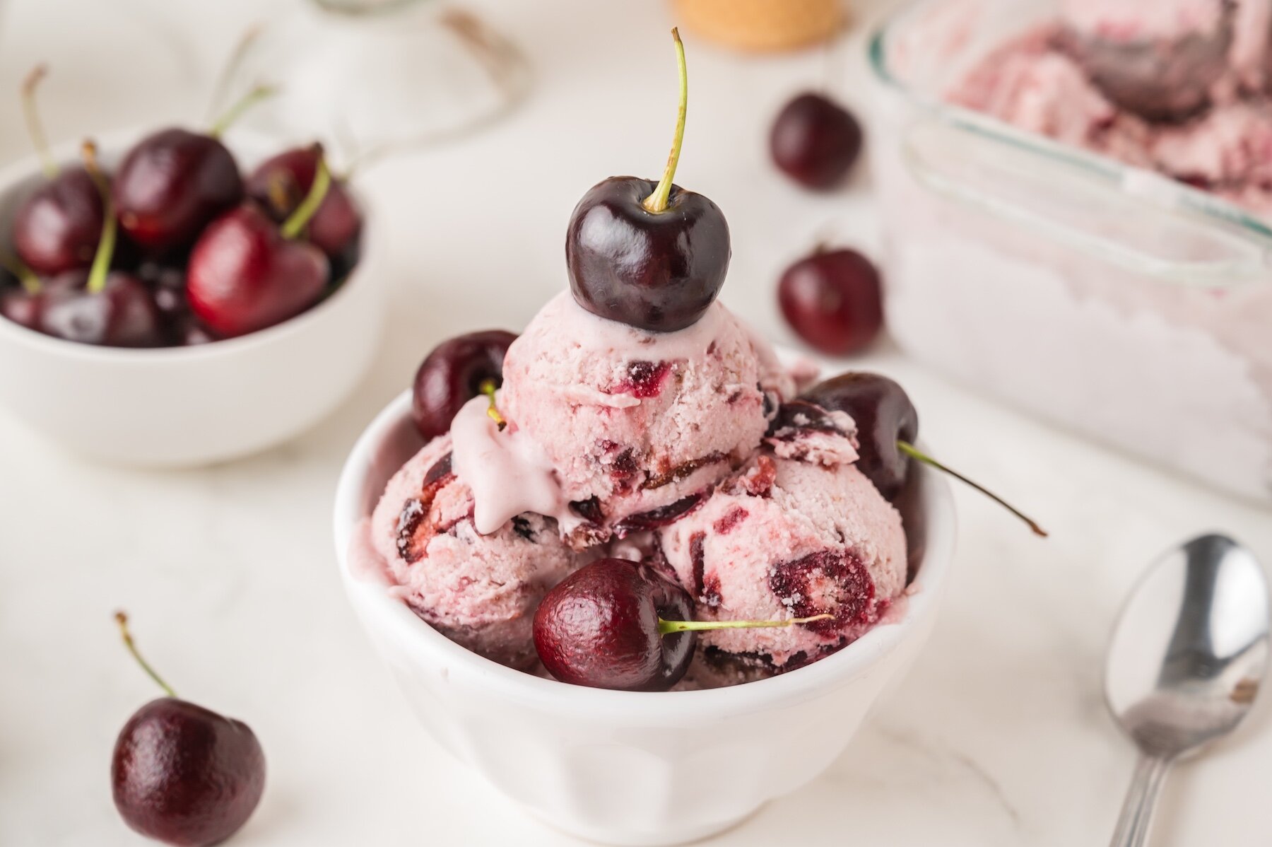 a bowl of no churn homemade cherry ice cream topped with fresh black cherries