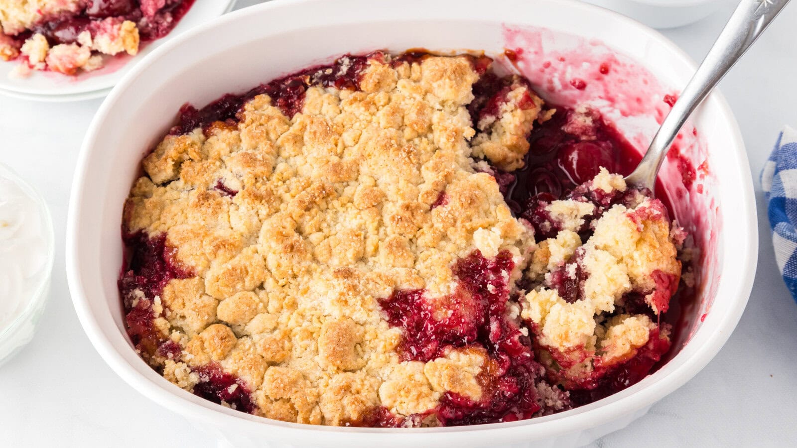 easy cherry cobbler with fresh cherries and a golden crust in a white baking dish