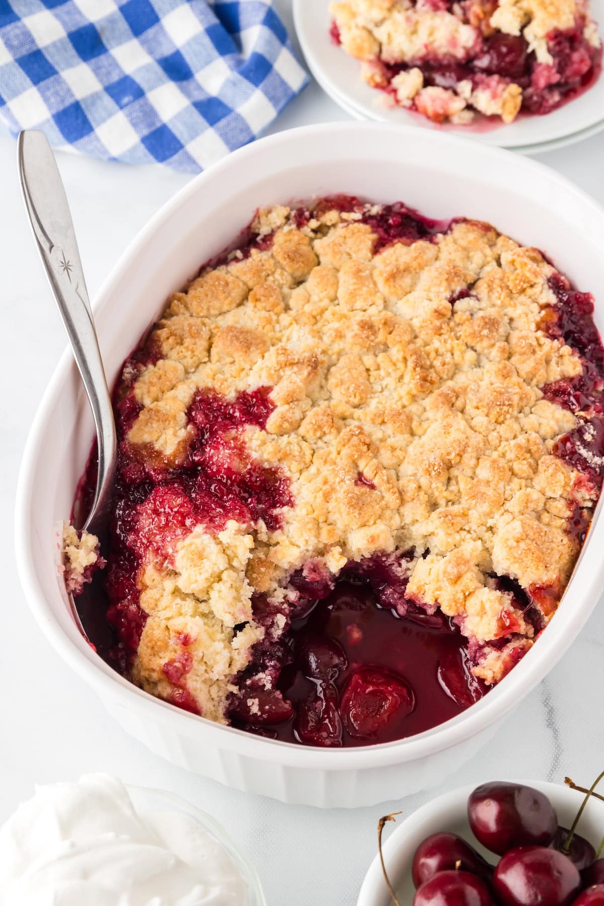 fresh cherry cobbler with a golden crust and fresh cherries in a white baking dish