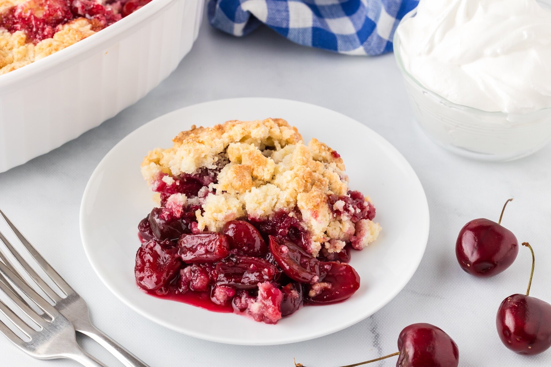 one serving of easy cherry cobbler with fresh cherries on a white plate