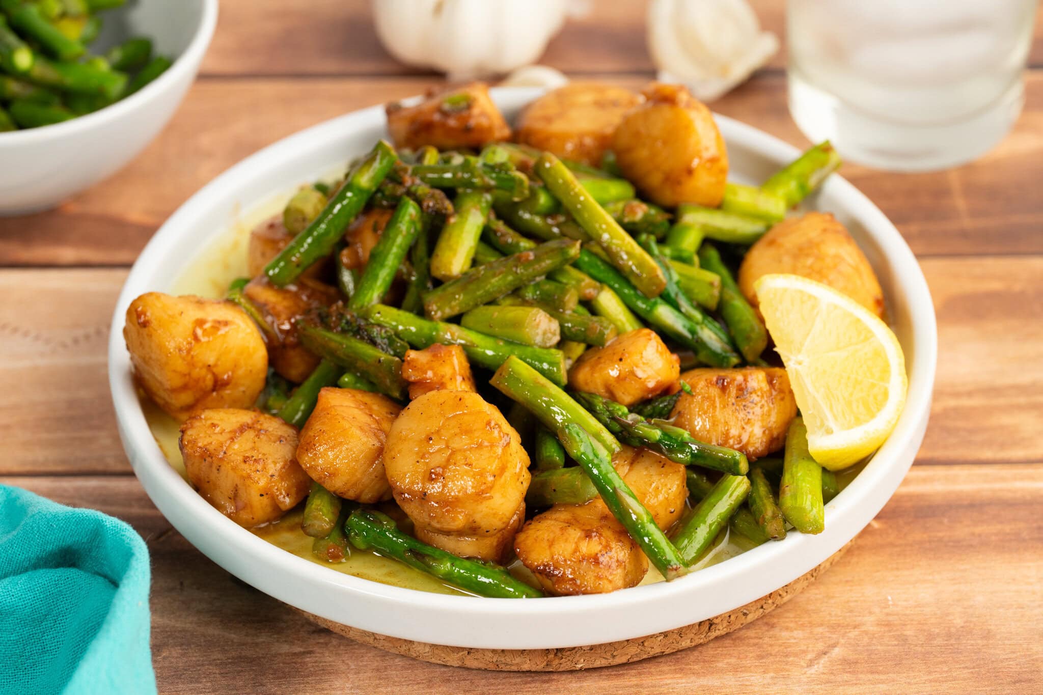 Scallops and pasta with asparagus in a white wine garlic butter sauce with a slice of lemon