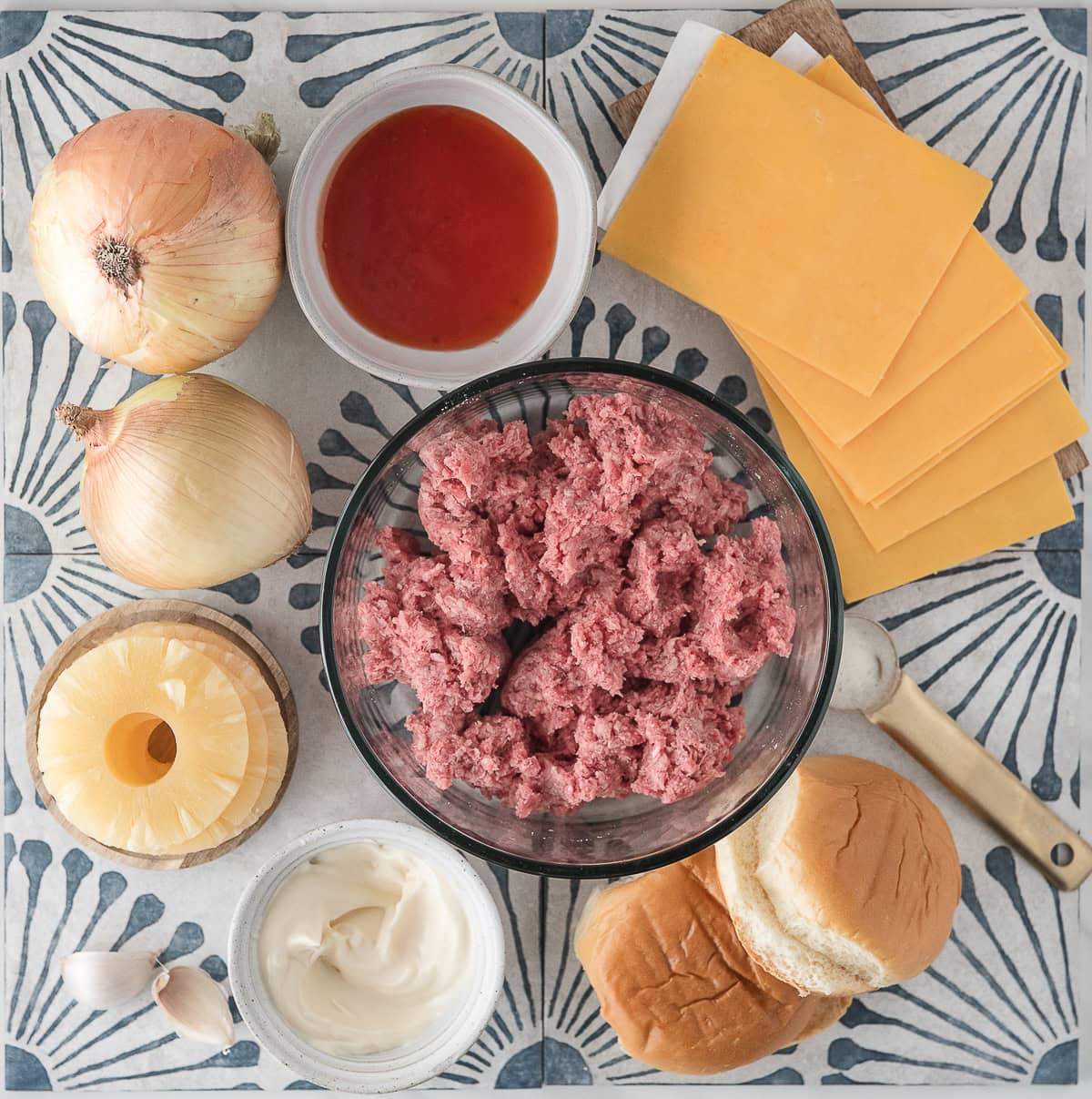Hawaiian burgers on the stove ingredients including ground beef, pineapple, sweet and sour sauce, Hawaiian rolls, cheddar cheese, and sweet onions