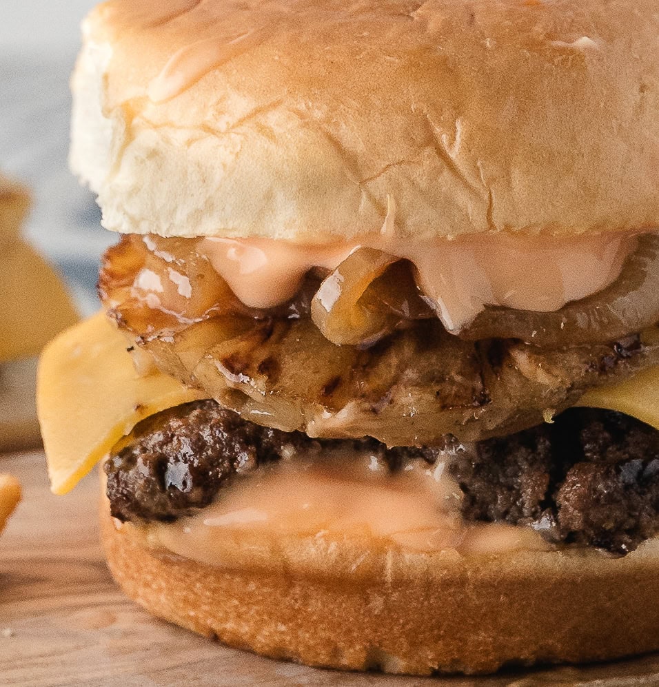 a close up of a Hawaiian burger with pineapple and caramelized onions after being cooked on the stove