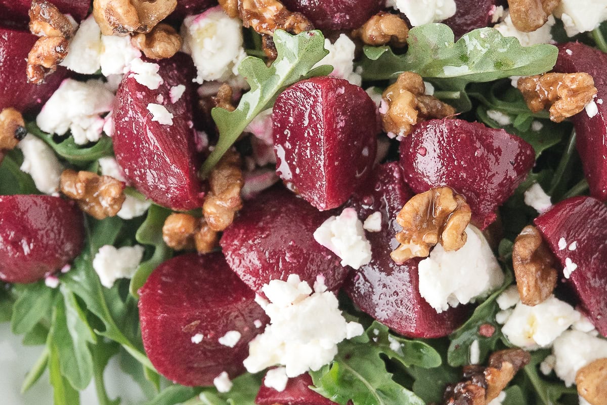 a close up of roasted beets in an arugula beet salad with feta