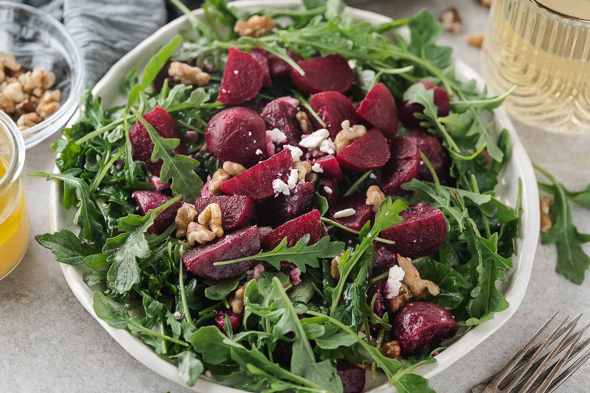 one serving of arugula beet salad with feta on a white plate