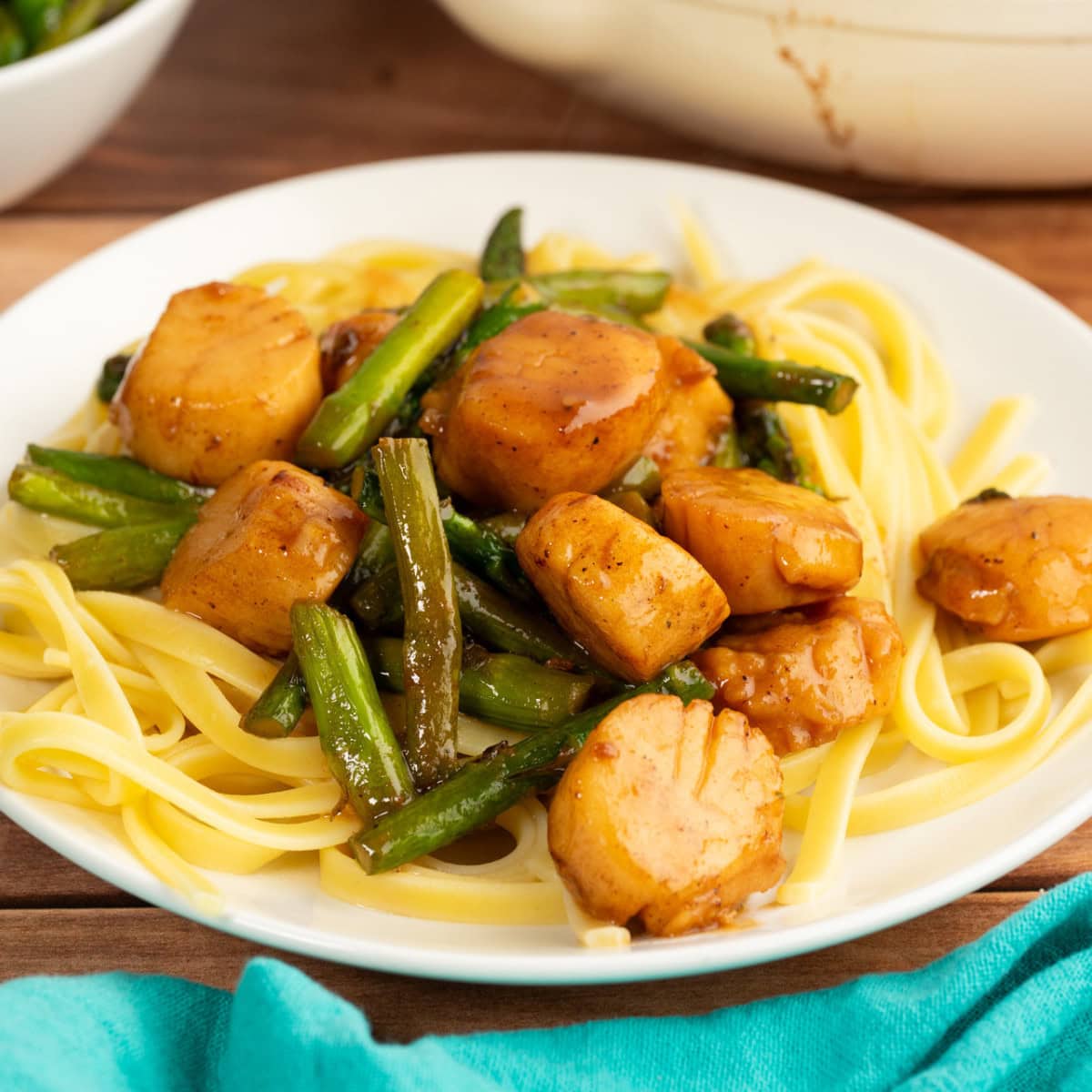 Scallops and pasta with asparagus in a white wine garlic butter sauce on a white plate