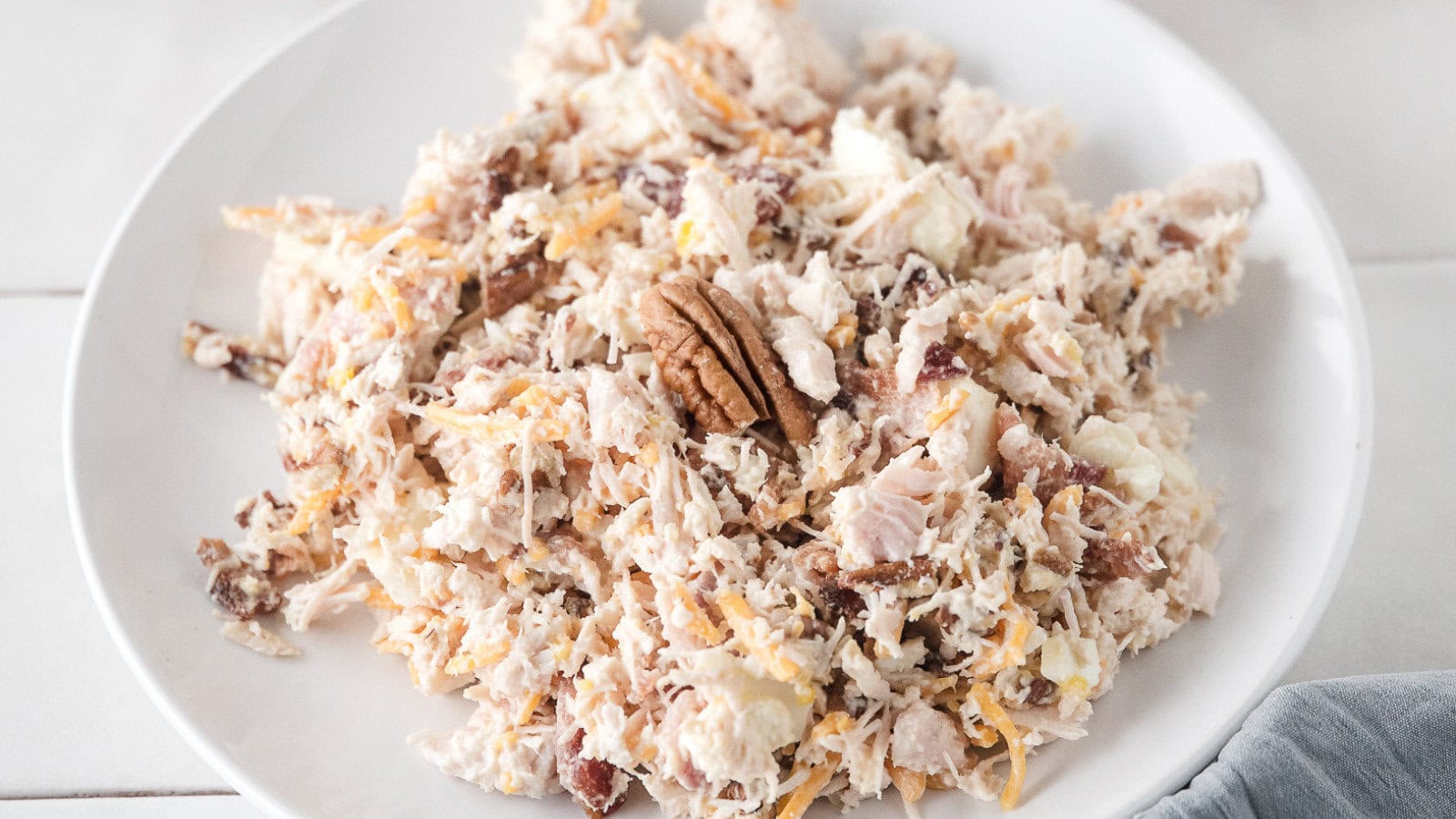 canned chicken salad topped with a pecan half on a white plate
