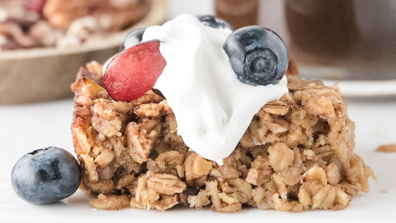 one serving of healthy baked oatmeal topped with fresh blueberries and cherries and whipped topping