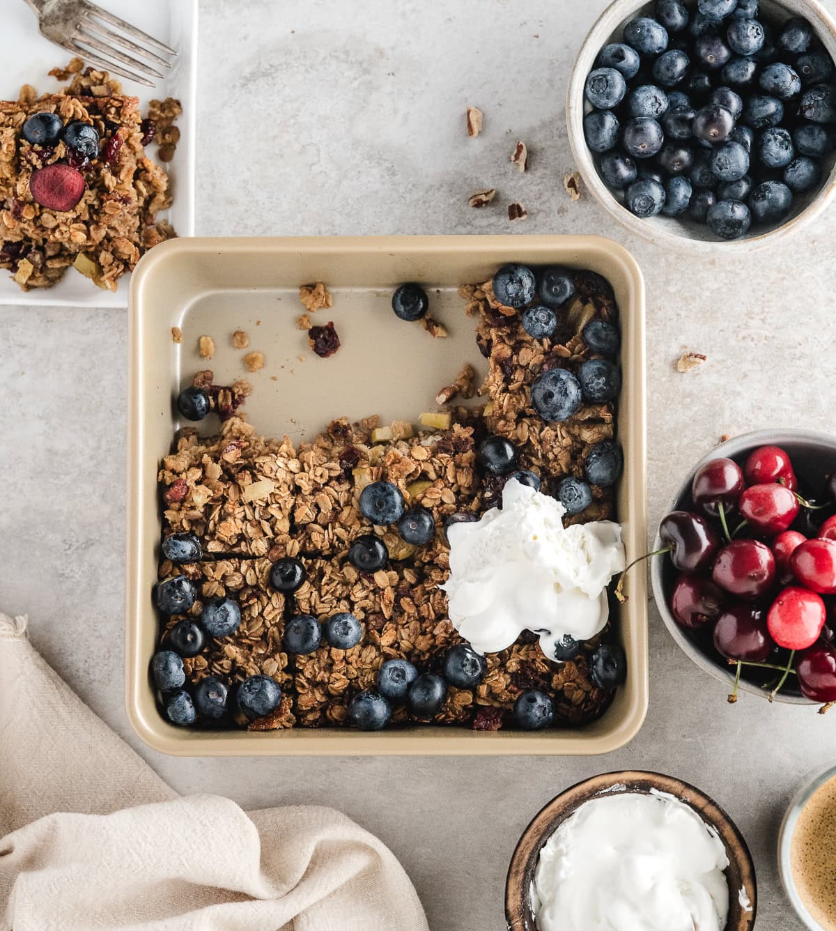 healthy baked oatmeal in the casserole dish with fresh blueberry, cherry, and whipped topping