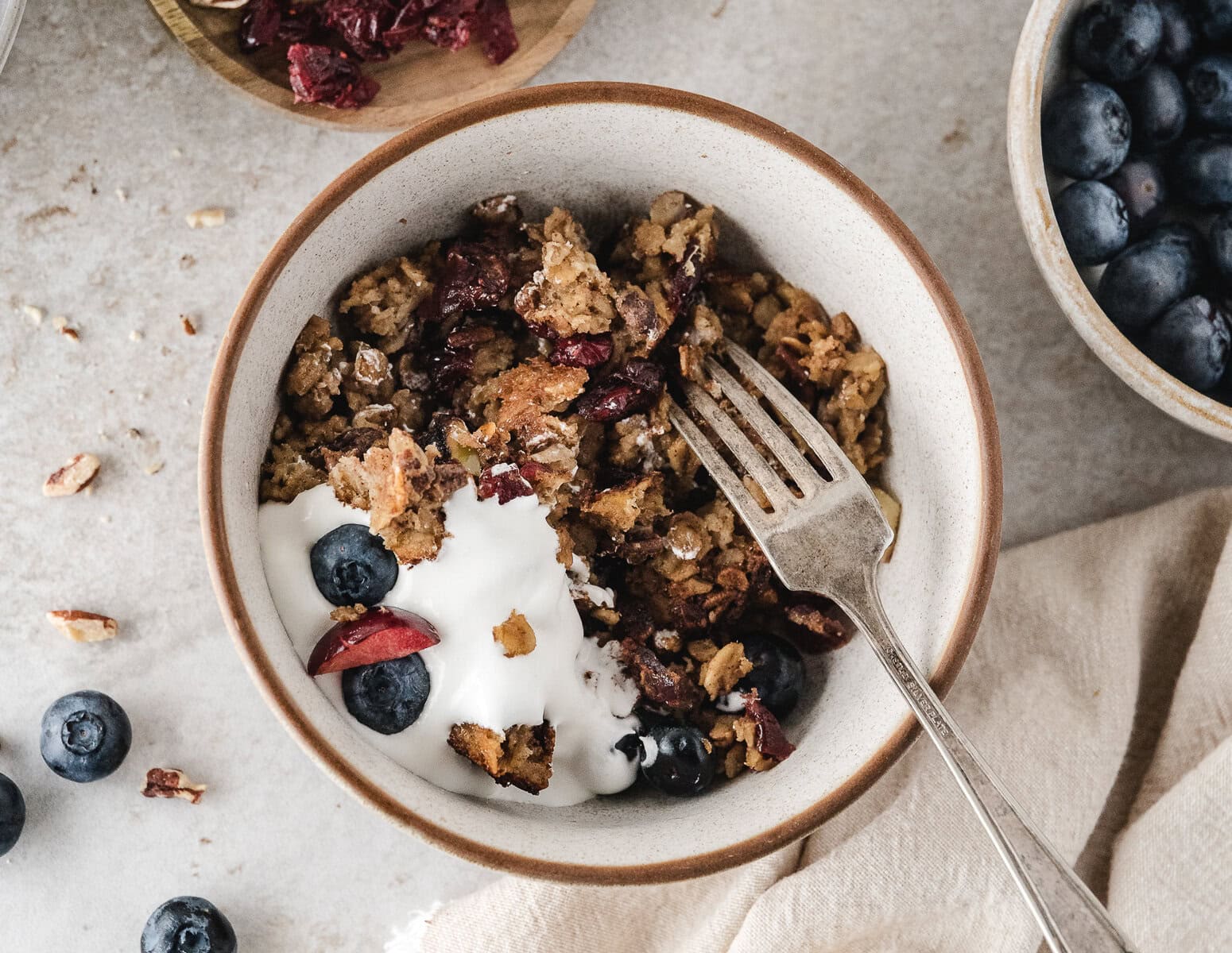 a bowl full of healthy baked oatmeal with fresh and dried fruits and whipped topping