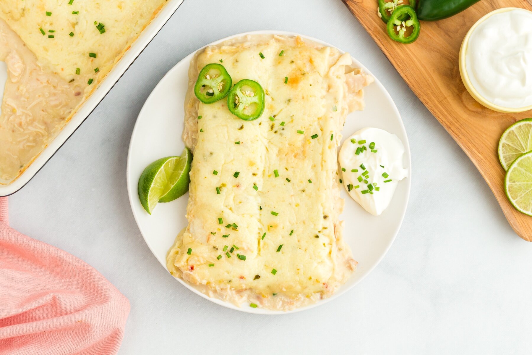 two Creamy White Chicken Enchiladas made with Cream of Chicken on a white plate with sliced jalapenos