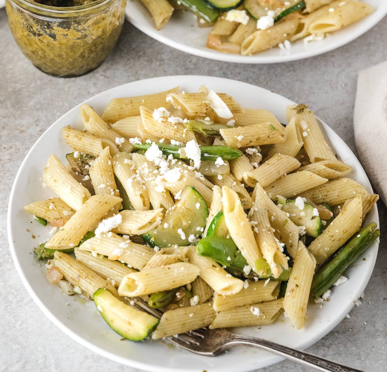 a close up of one serving of easy pasta primavera on a white plate with a fork