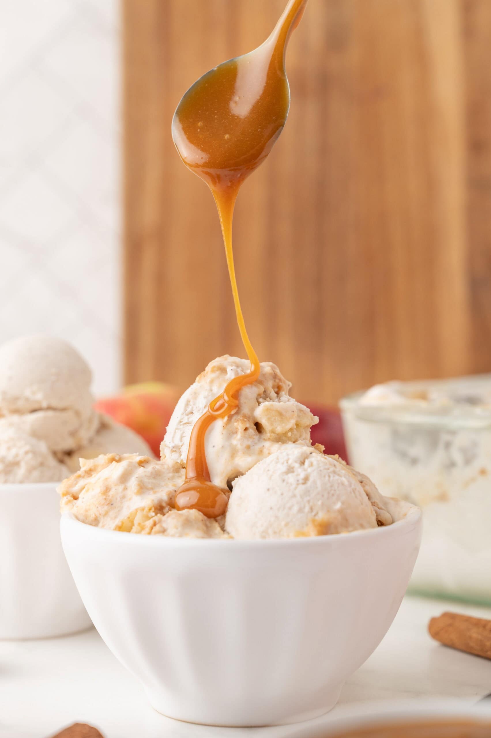 Caramel sauce drippiig from a spoon topping the Apple pie ice cream