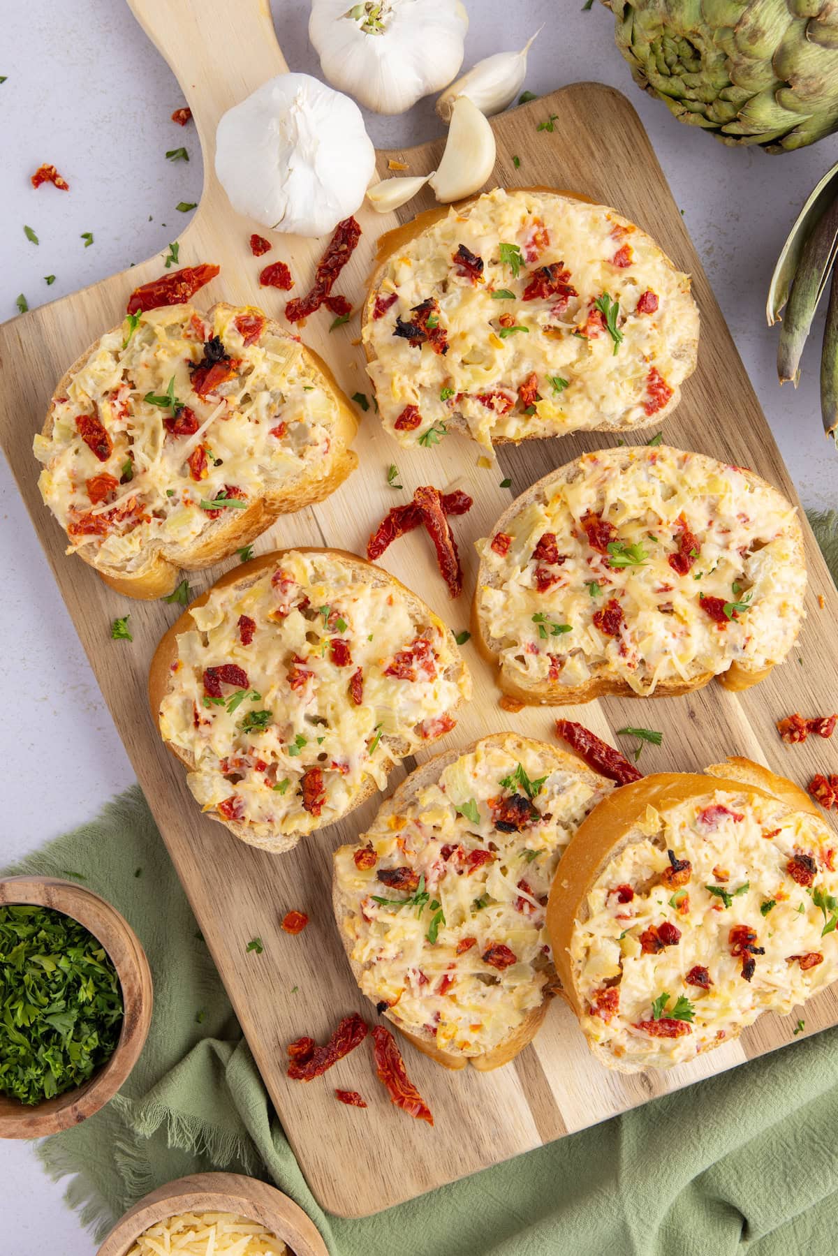 seven slices of Artichoke Bruschetta with Sun-Dried Tomatoes on a cutting board