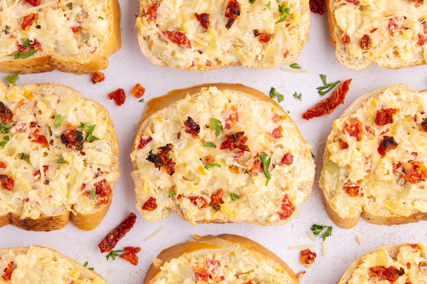 nine slices of Artichoke Bruschetta with Sun-Dried Tomatoes on a white countertop