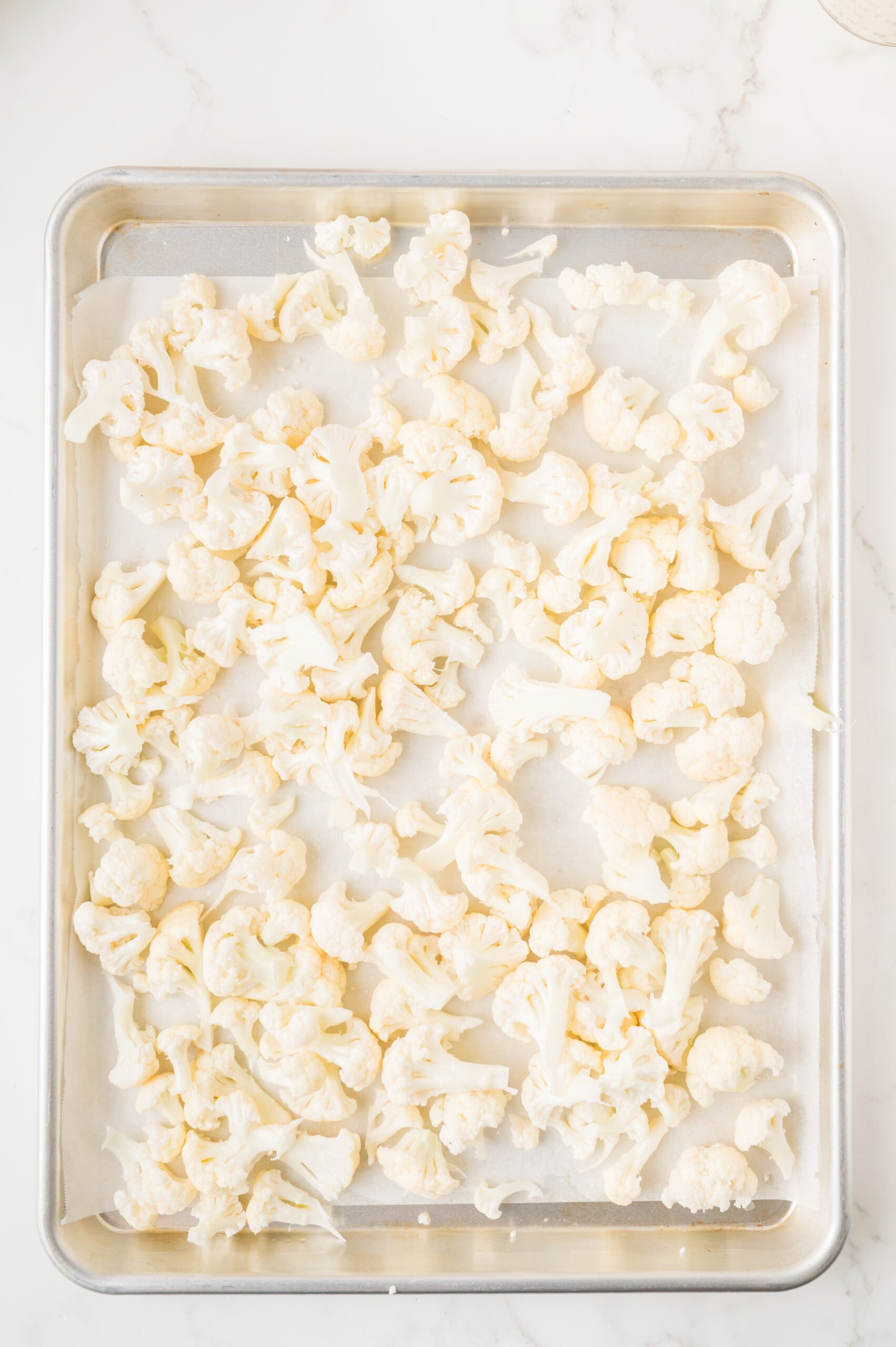 Cauliflower on baking sheet with oil drizzled, ready to be baked