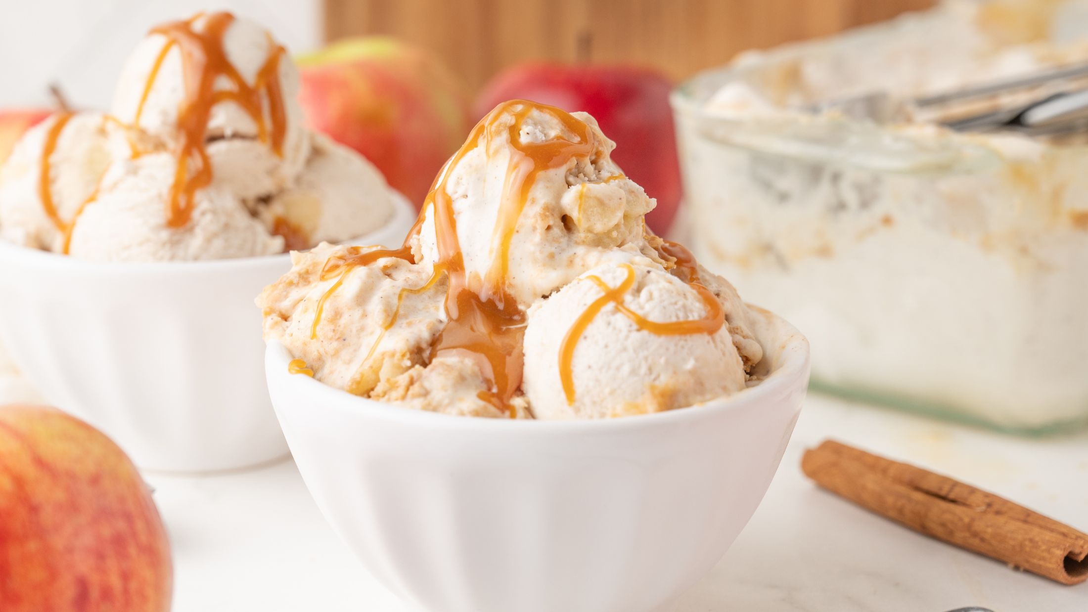 Apple pie ice cream served in a bowl with several scoops and caramel sauce on top
