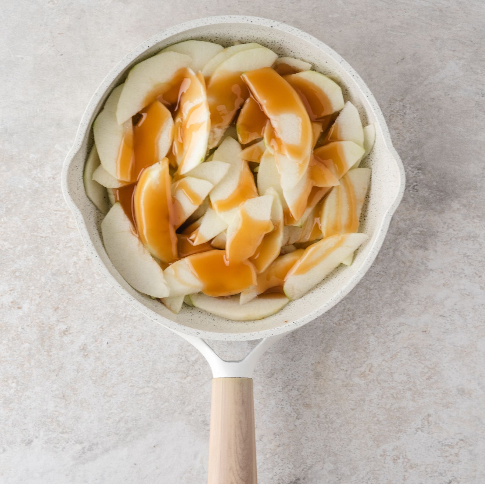 All apples cored and peeled in baking skillet with caramel dripped over the apples
