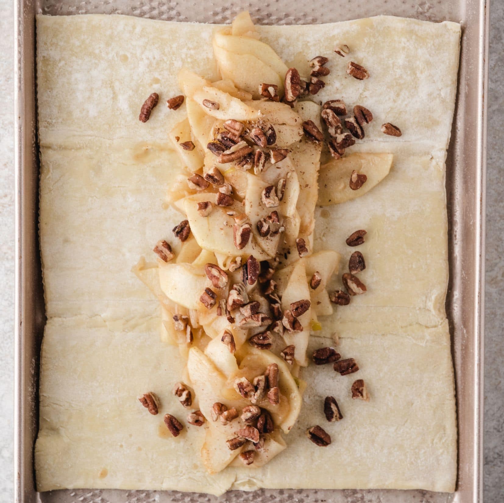 Apples softened with caramel mixture, added pecans on top of puff pastry. It's ready to be rolled up to finish the recipe