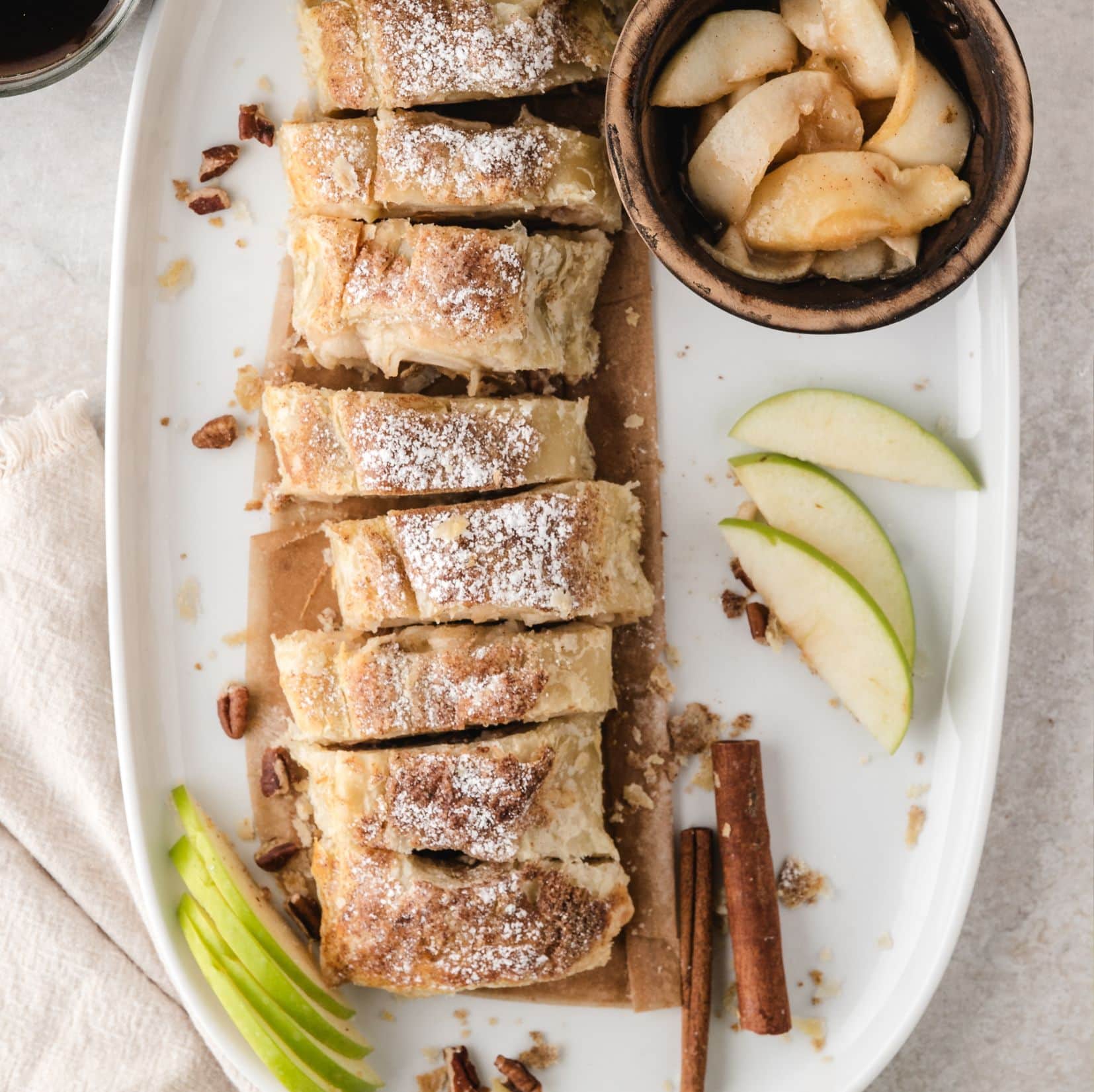Fresh out of the oven, the apple strudel is cut into slices, powdered sugar on top dusted lightly and ready to be plated