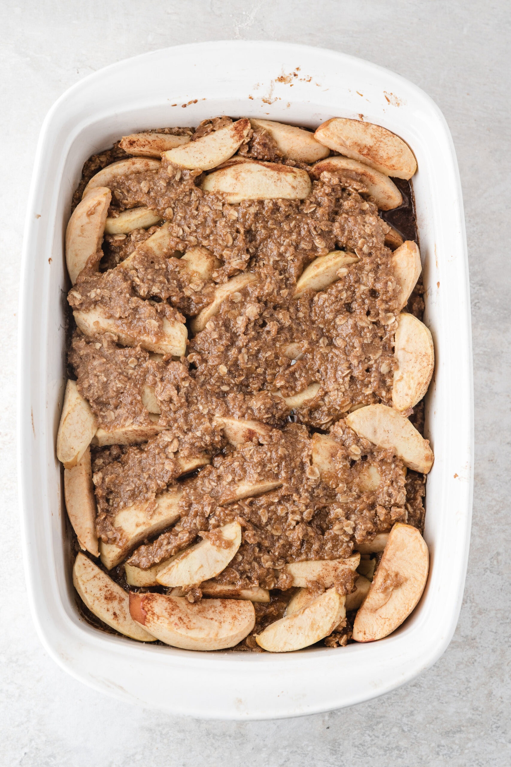 easy apple crisp with oats has the layers shown of the oat and flour mixture with apples layered on top and then an additional layer of the oat mixture